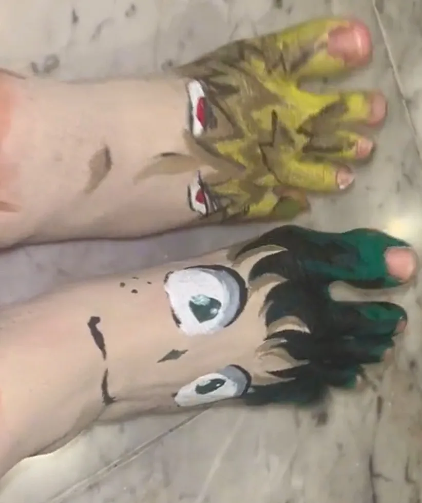 Two feet are painted to resemble anime characters, one with yellow skin and red eyes, the other with black hair and large…