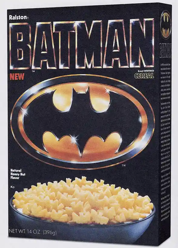 The image shows a vintage Ralston Batman cereal box, featuring the iconic Batman logo and a bowl of yellow, puffed cereal…