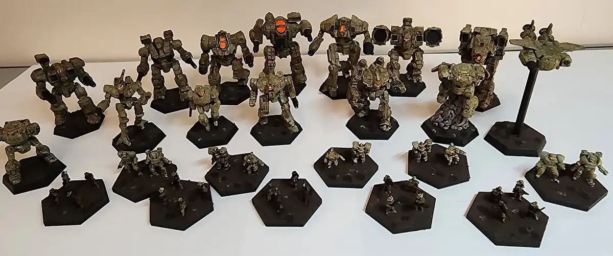 A collection of painted miniature mechs and infantry figures on hexagonal bases arranged on a white surface. The mechs vary…