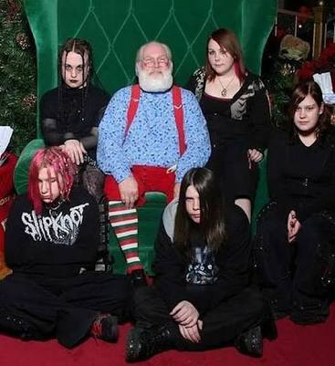 A group of six people, including a man in a Santa-like outfit with red suspenders and striped socks, pose for a photo in…
