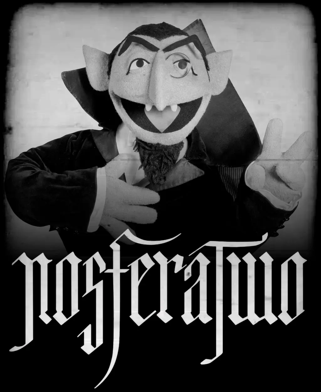 A black-and-white image of a puppet dressed as a vampire with pointed ears, fangs, and a cape, making a peace sign with one…
