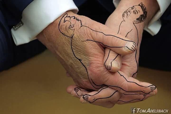 two hands are held together, outlined with black lines to form the shapes of a baby and an adult. The baby's hand, drawn…