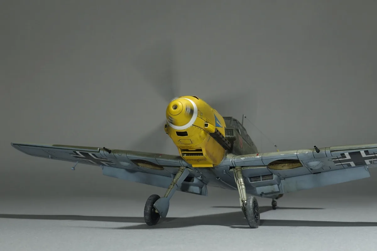A detailed scale model of a World War II-era German fighter plane, likely a Messerschmitt Bf 109, is shown from a low…