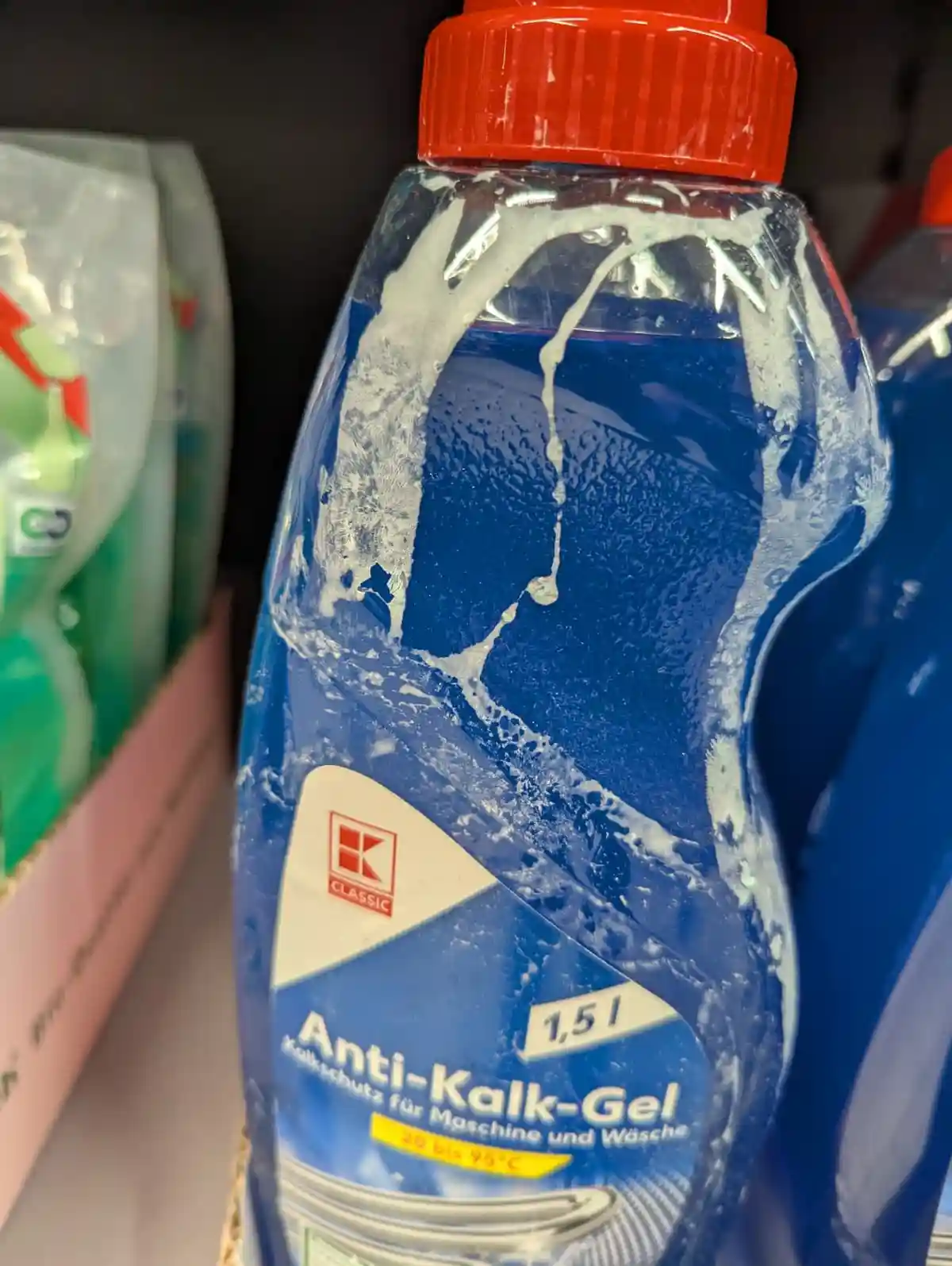 A close-up of a blue bottle of 'Anti-Kalk-Gel' (anti-lime scale gel) with a red cap, visibly covered in white, dried residue…