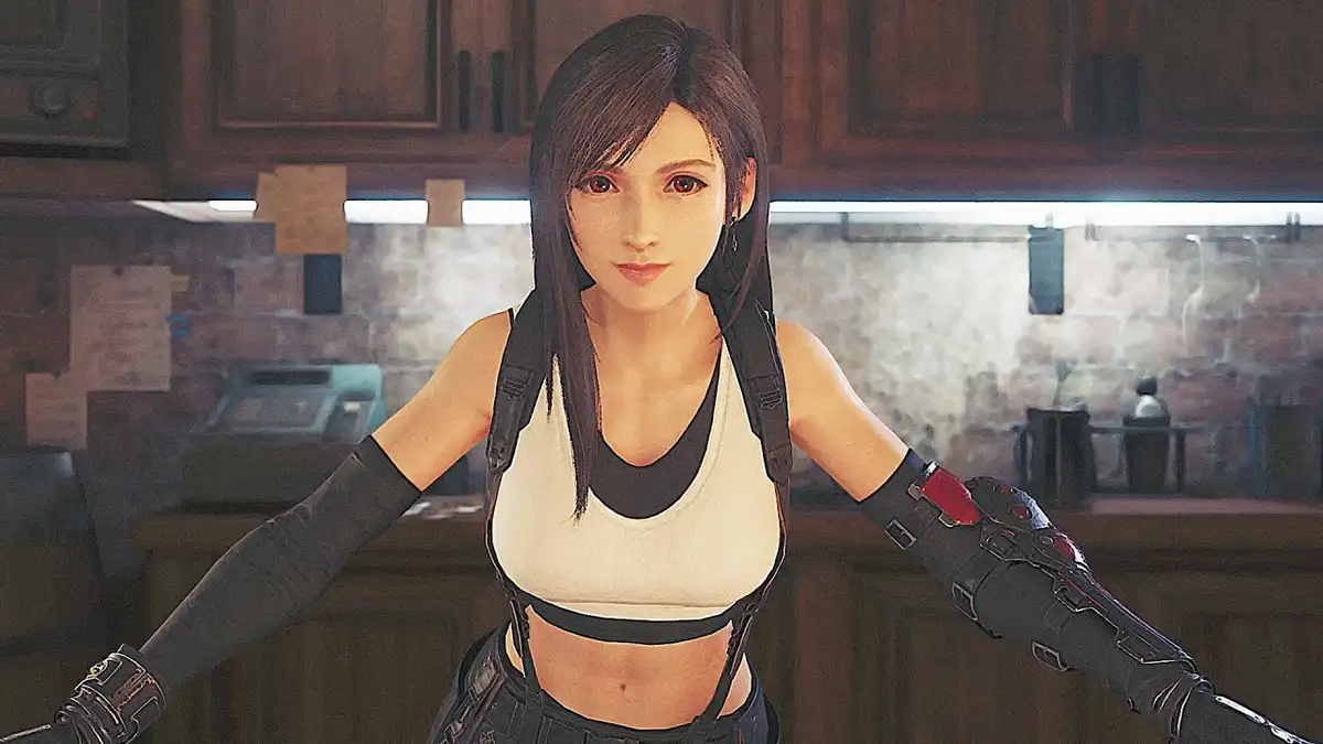 A female video game character with dark hair and a white crop top stands in a kitchen with wooden cabinets and a brick wall…