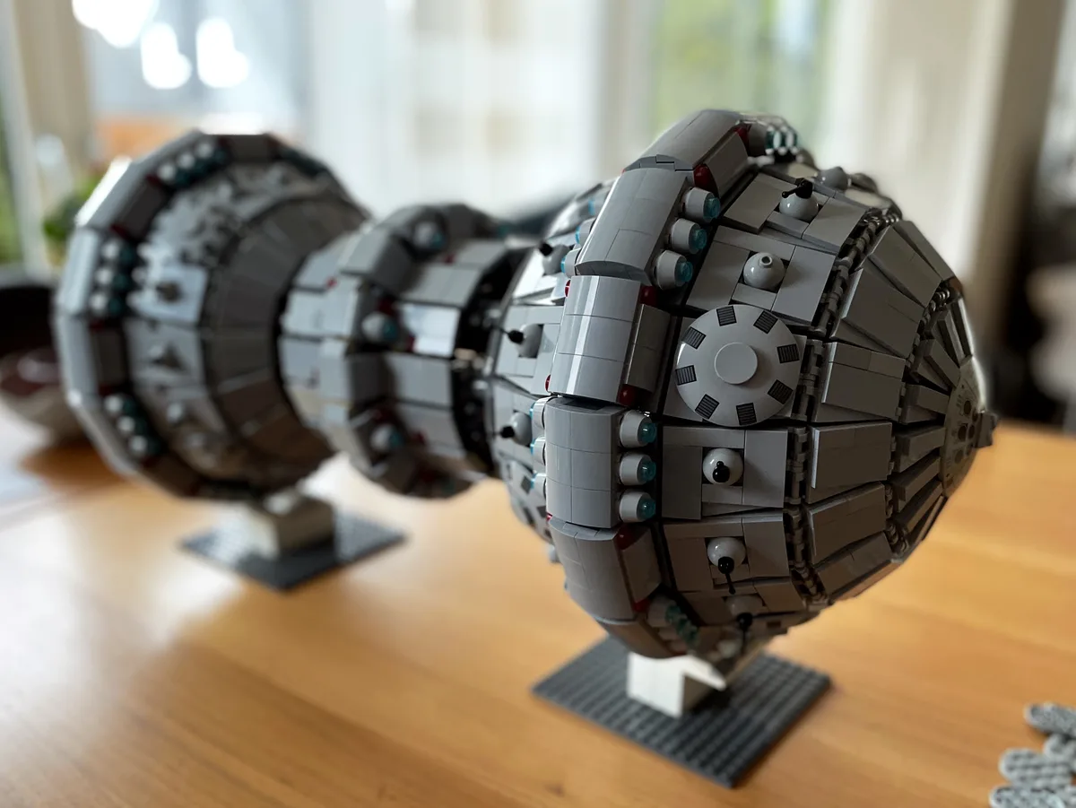 A close-up photo shows two detailed LEGO models of the Death Star from Star Wars, constructed with grey, white, and black…