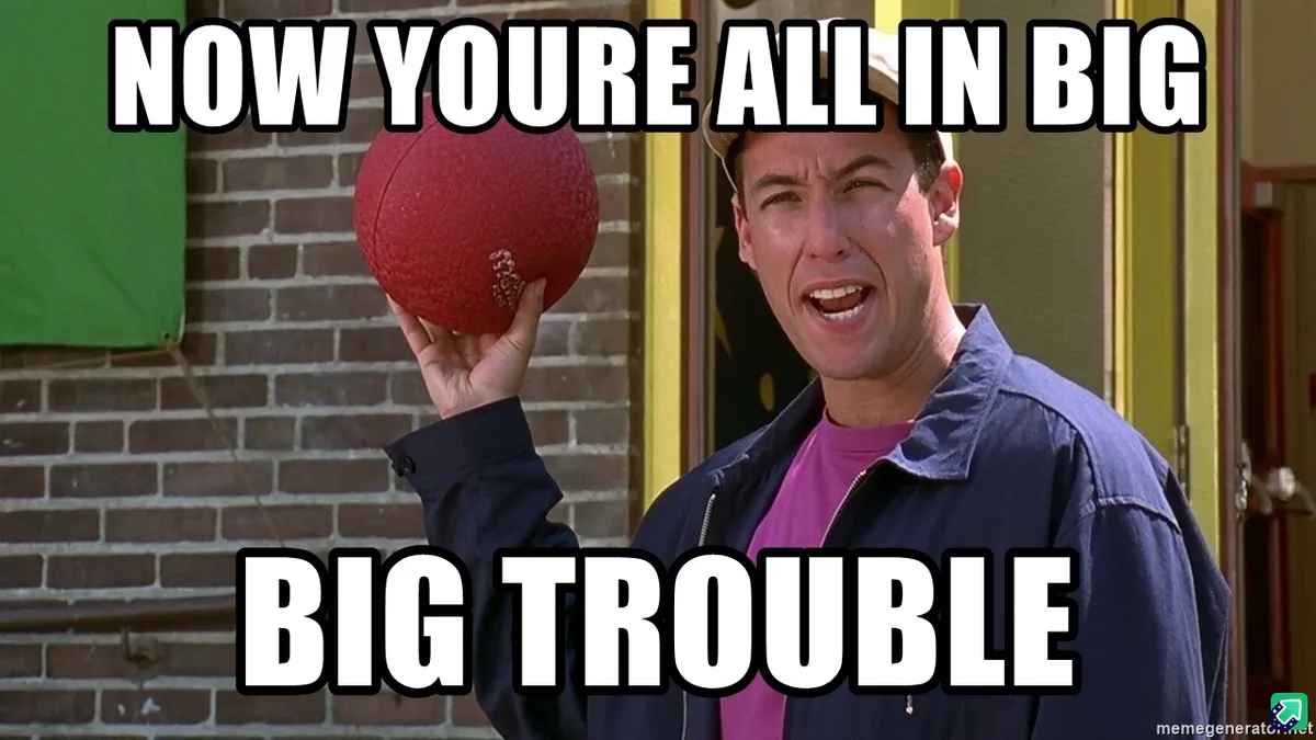 A man in a blue jacket and pink shirt holds a red football while standing in front of a brick wall, with the text 'NOW YOURE…