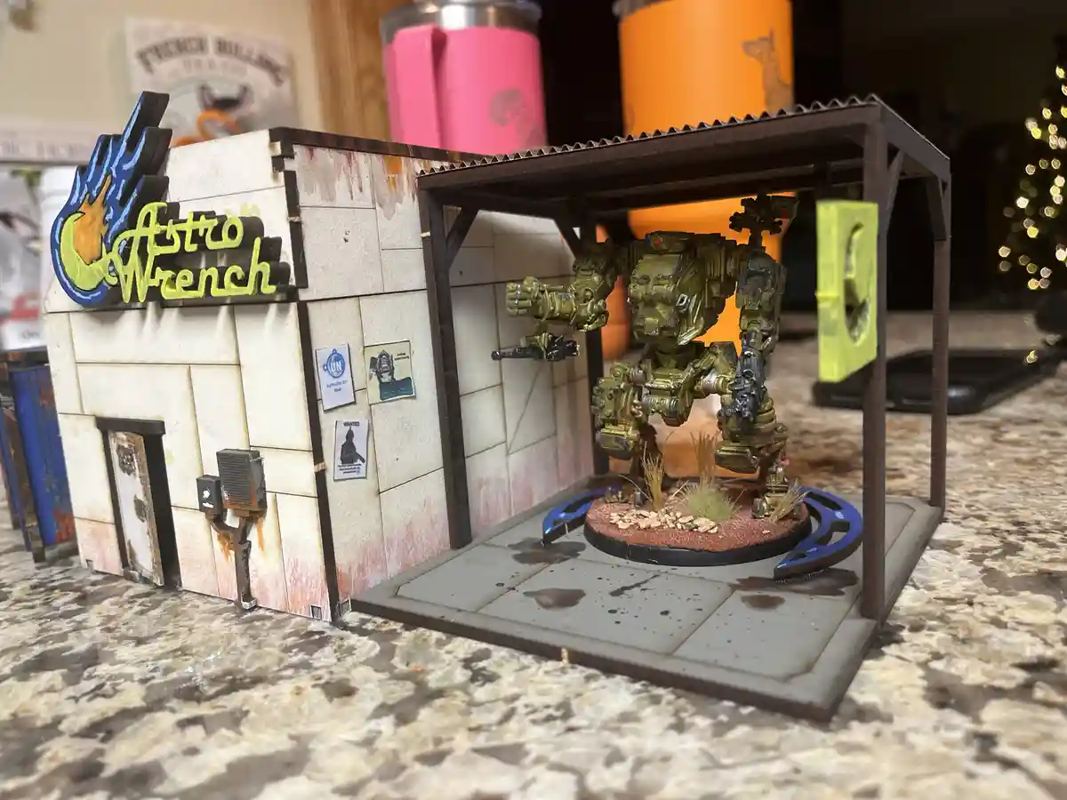 A miniature diorama of a weathered, sci-fi themed garage named 'Astro Wrench' with a large, detailed yellow and black…