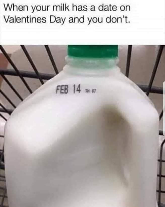A close-up photo of a white plastic milk jug with a green cap, sitting in a black wire shopping cart. The jug has a printed…
