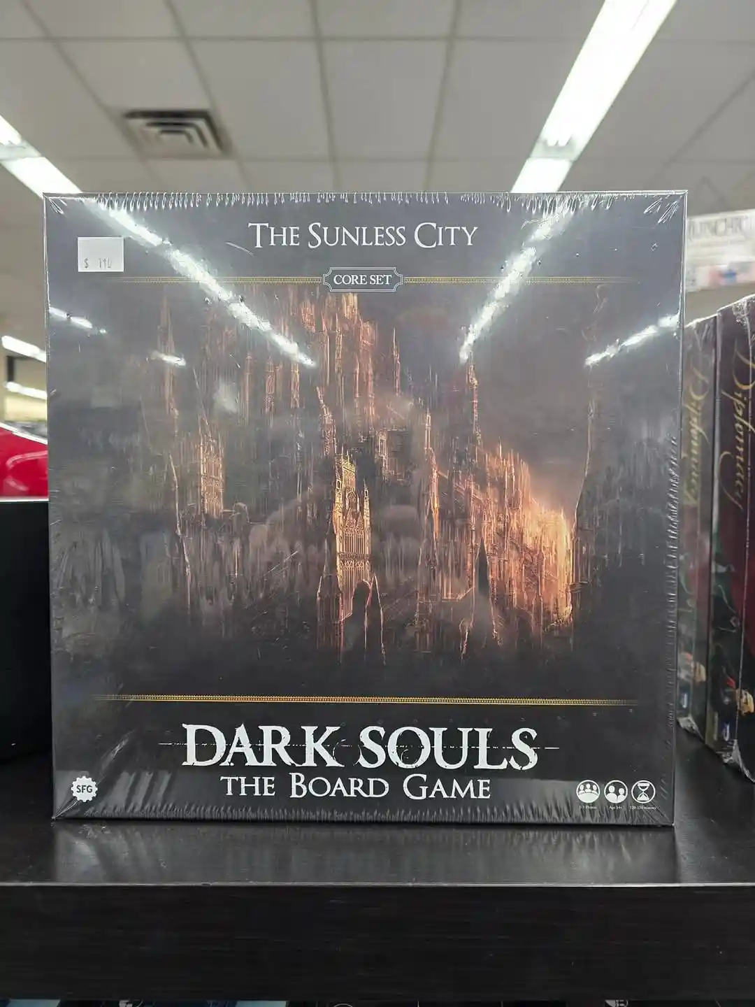 A sealed board game box for 'Dark Souls: The Board Game' featuring 'The Sunless City' core set, displayed on a store shelf…