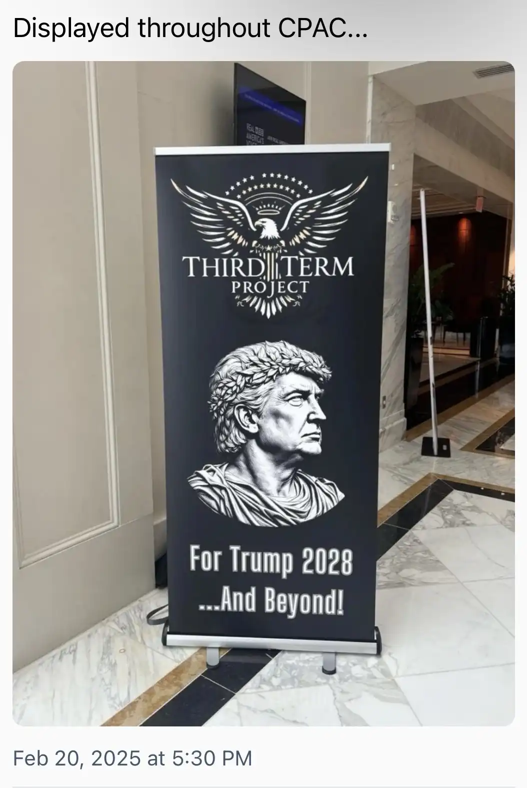 A black banner standee at a convention displays a logo with an eagle and stars above the text 'THIRD TERM PROJECT'. Below…