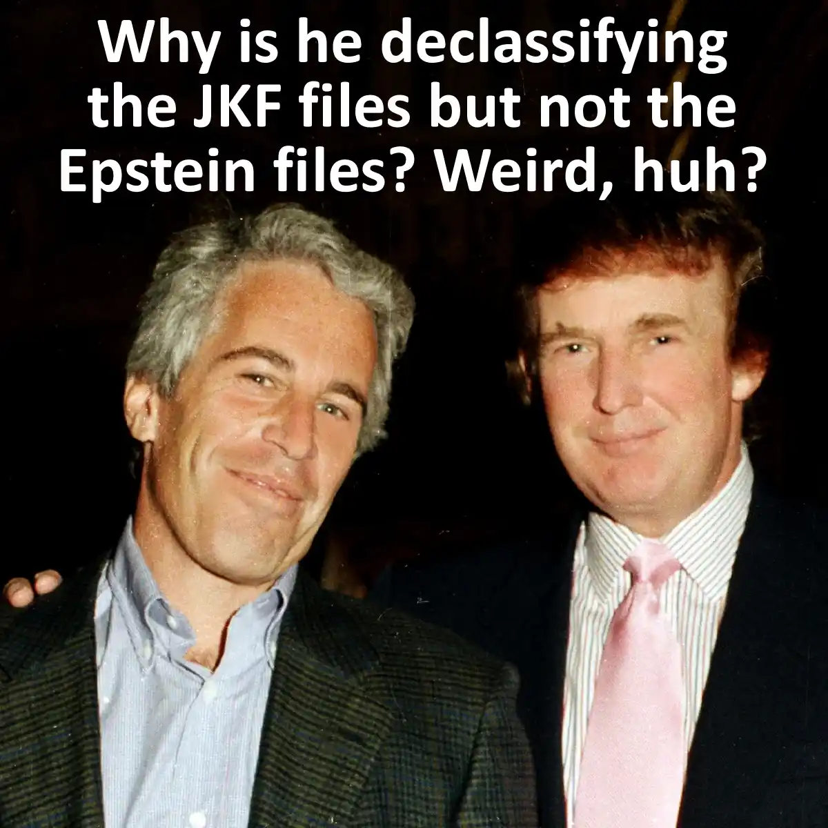 The image shows two men posing together; the man on the left has gray hair and wears a dark jacket over a light blue shirt…