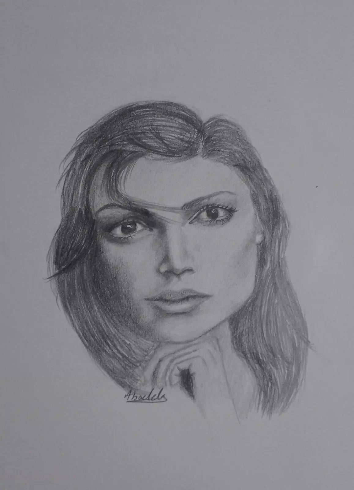 A pencil sketch of a woman with shoulder-length hair, looking directly at the viewer with her hand resting under her chin…