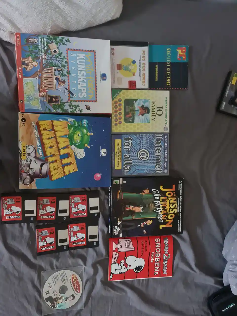 An overhead photo shows a collection of old educational and entertainment PC software, including Swedish language learning…