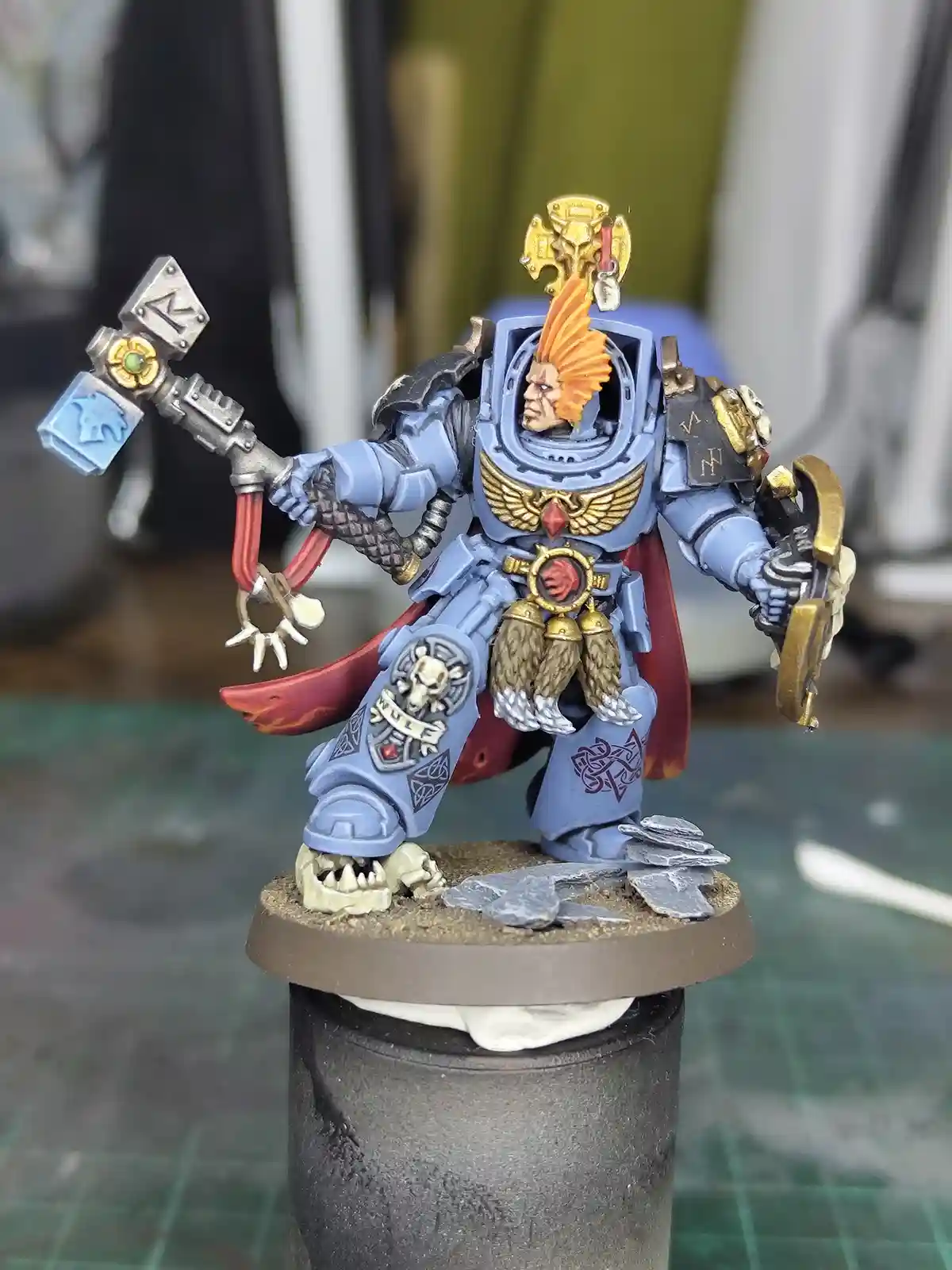 A highly detailed, hand-painted miniature of a Space Marine from Warhammer 40,000, wearing blue armor with gold accents…