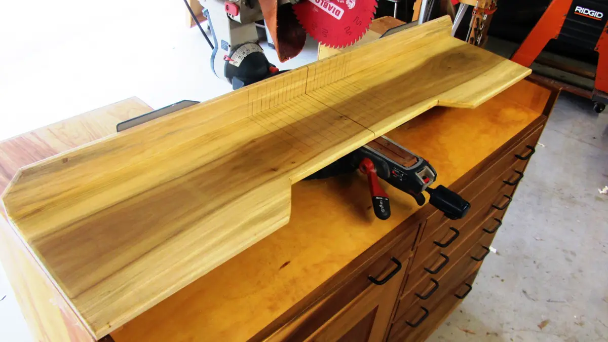 A large, custom-made wooden desk with a routed edge and grid lines is shown resting on a wooden cabinet with multiple…