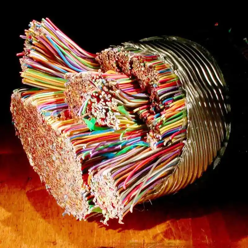 A cross-section of a large, colorful cable bundle reveals hundreds of individual wires fanned out, with some frayed and…