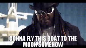A man with dreadlocks, a black hat, and white sunglasses stands confidently in front of a large boat, with the overlaid text…