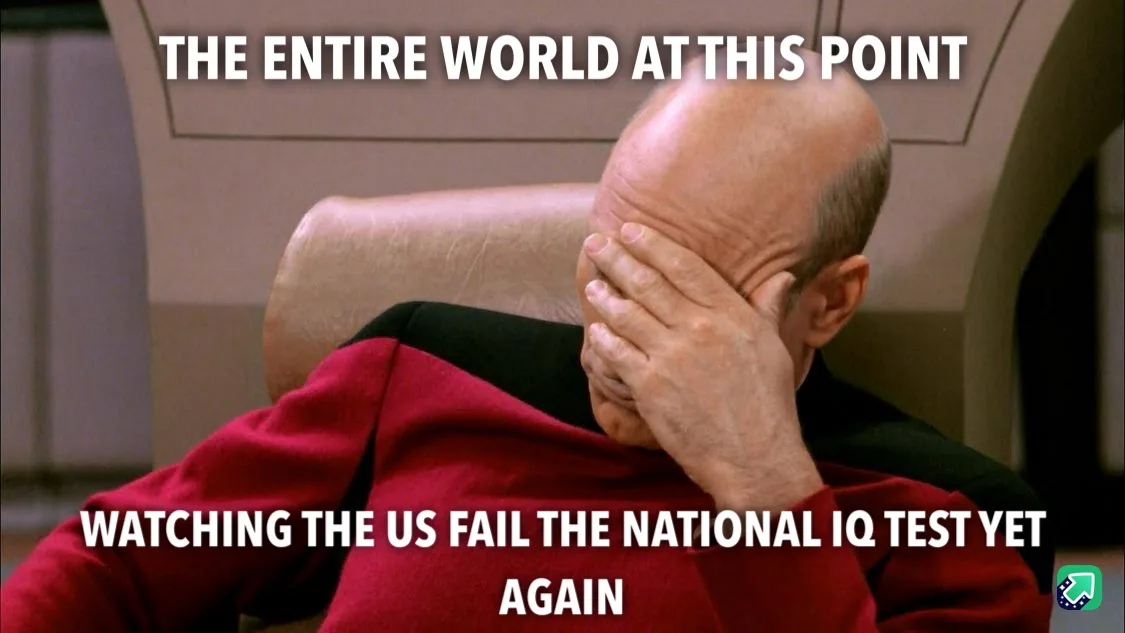 A bald man in a red Starfleet uniform sits in a chair, covering his face with his hand in a gesture of despair or…