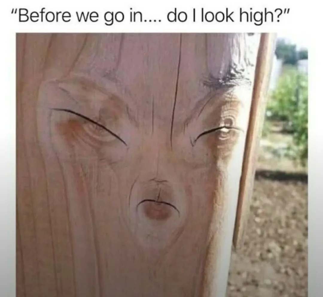 A close-up photo of a wooden post with natural grain patterns that resemble a face with squinted eyes and a slightly open…
