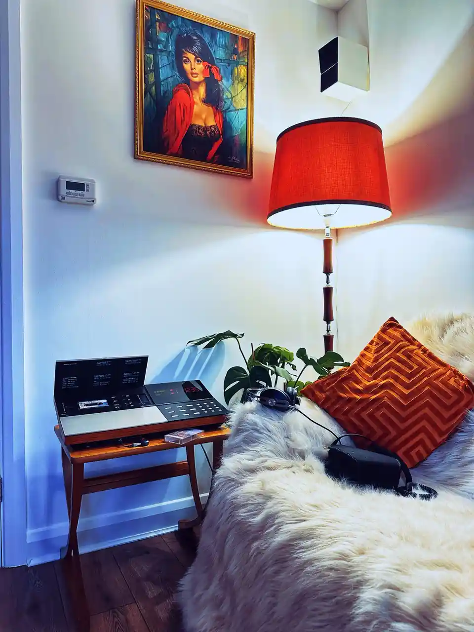 A cozy room corner features a vintage-style cassette player on a wooden side table, next to a fluffy white couch with an…