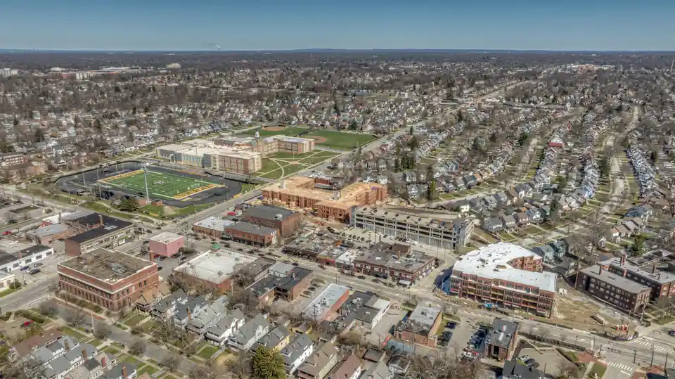 An aerial photo of a suburban town with a school, football field, and residential neighborhoods. Overlaid text reads 'i'm…