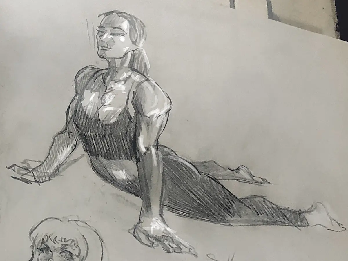 A pencil sketch of a muscular person in a seated pose, smiling with eyes closed, wearing a tank top. The drawing is on a…