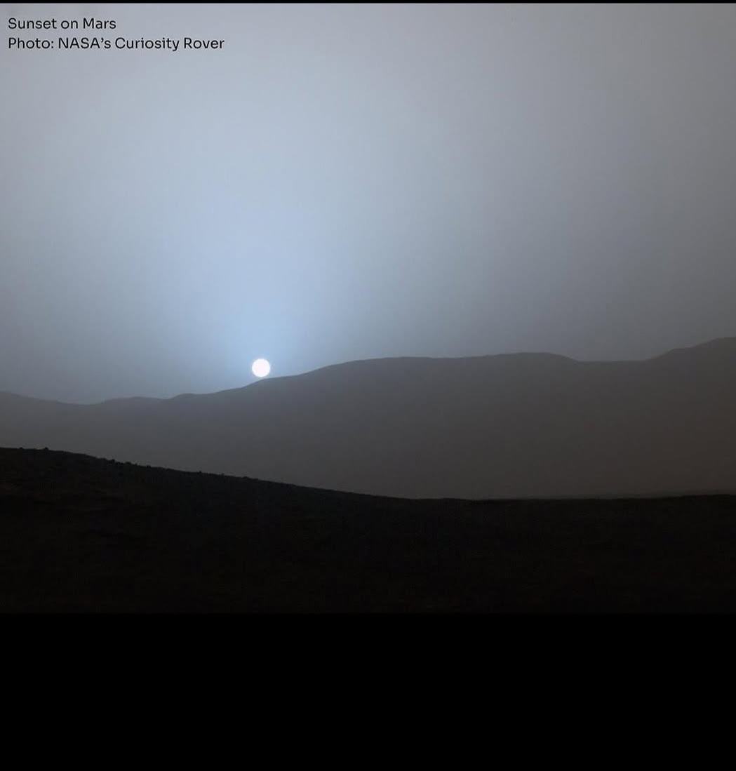 A photograph from NASA's Curiosity Rover shows a pale sun setting behind a hazy Martian horizon, casting a dim glow over…