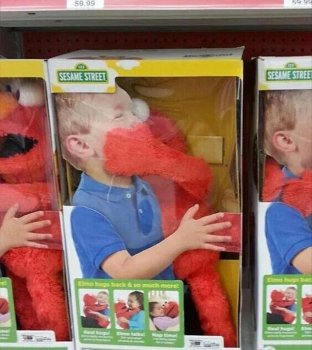 A toy box for a Sesame Street Elmo plush shows a young boy with his face obscured by the toy's red fur, appearing to be…