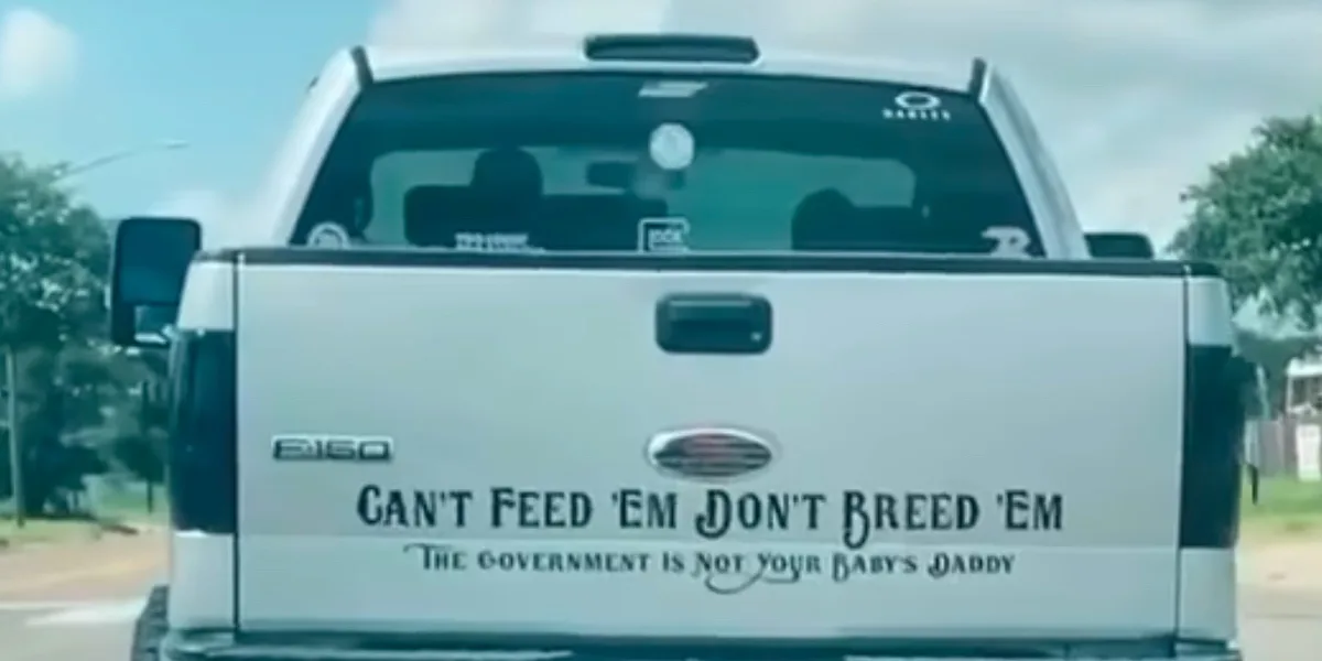 The rear of a white Ford F-150 pickup truck is shown, featuring a large decal with the text 'CAN'T FEED 'EM DON'T BREED 'EM'…