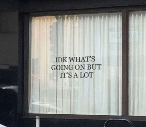 A photo of a window with sheer curtains, overlaid with the text 'IDK WHAT'S GOING ON BUT IT'S A LOT' in a simple black font…