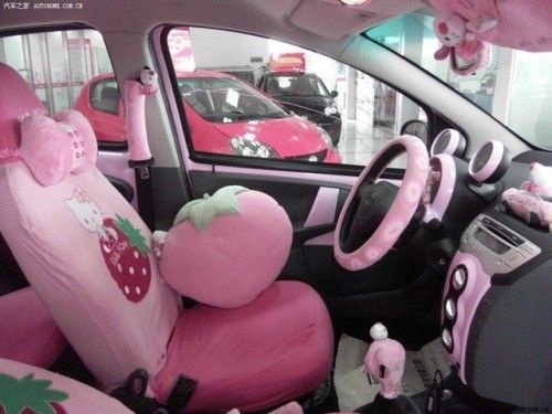 the interior of a car is covered in pink plush accessories including a strawberry-themed seat cover, a large plush…