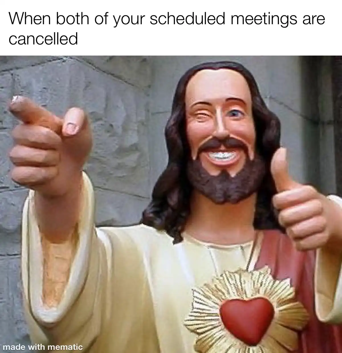 A statue of Jesus Christ with a cheerful, slightly exaggerated smile, one hand pointing forward and the other giving a…