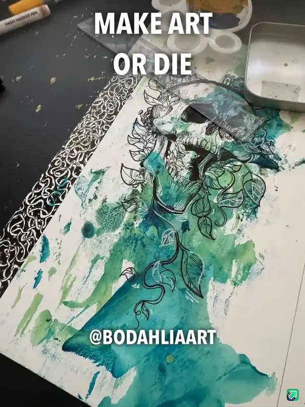 An overhead photo of a partially completed artwork on paper, featuring a stylized skull with floral elements and teal/green…