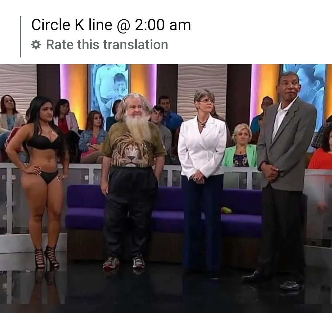A still from a TV show featuring four people standing in a line on a stage, with a woman in a bikini on the far left, a man…
