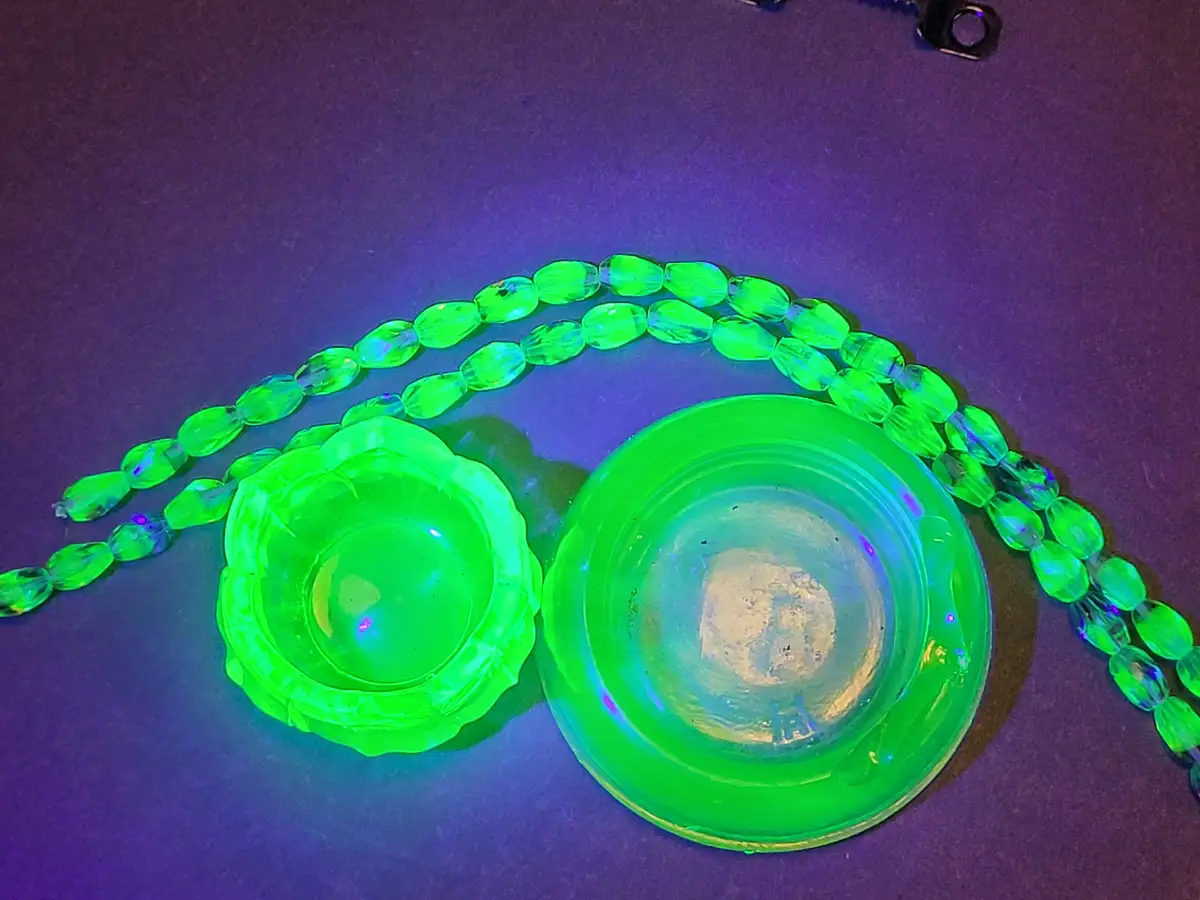 A close-up photo shows two bright green, glowing plastic glasses under blacklight, one with a scalloped rim and the other…