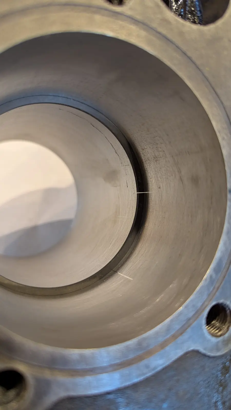 A close-up photo of a machined metal cylinder, likely an engine block or similar mechanical part, showing a circular groove…