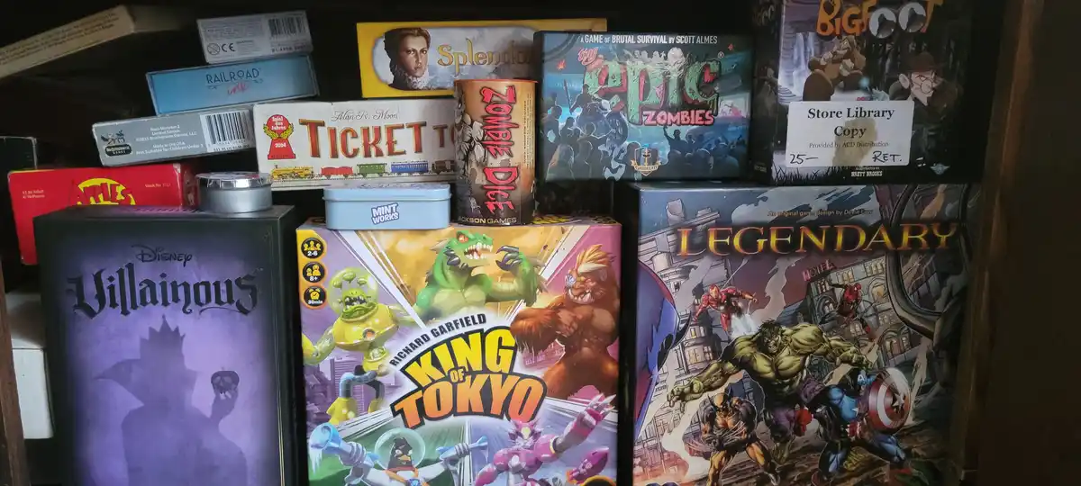 A shelf filled with various board game boxes, including 'Villainous', 'King of Tokyo', 'Legendary', 'Ticket to Ride'…