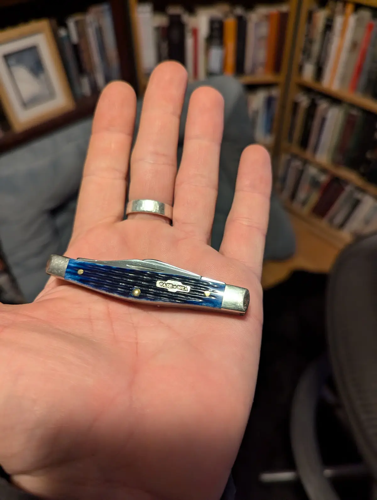 A person's open palm displays a small, blue-handled Case USA pocket knife, which is visibly much smaller than the hand…