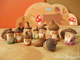 A collection of small, handcrafted acorn figurines, each with a painted face, beard, and tiny hat, arranged on a wooden…