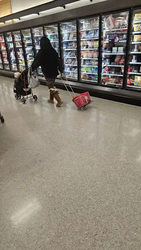 A person walks through a Target store aisle, pulling a red shopping basket with a handle that is visibly detached and…
