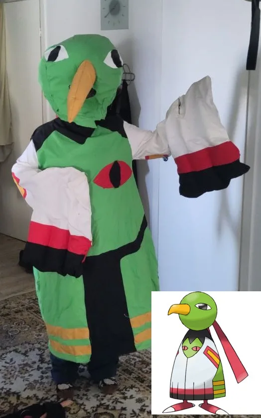 A person in a full-body costume of the Pokémon bird character, Pidgey, stands indoors holding up their gloved hands. The…