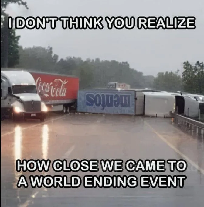 A rainy highway scene shows a Coca-Cola branded semi-truck driving toward a severely damaged, overturned semi-truck with a…