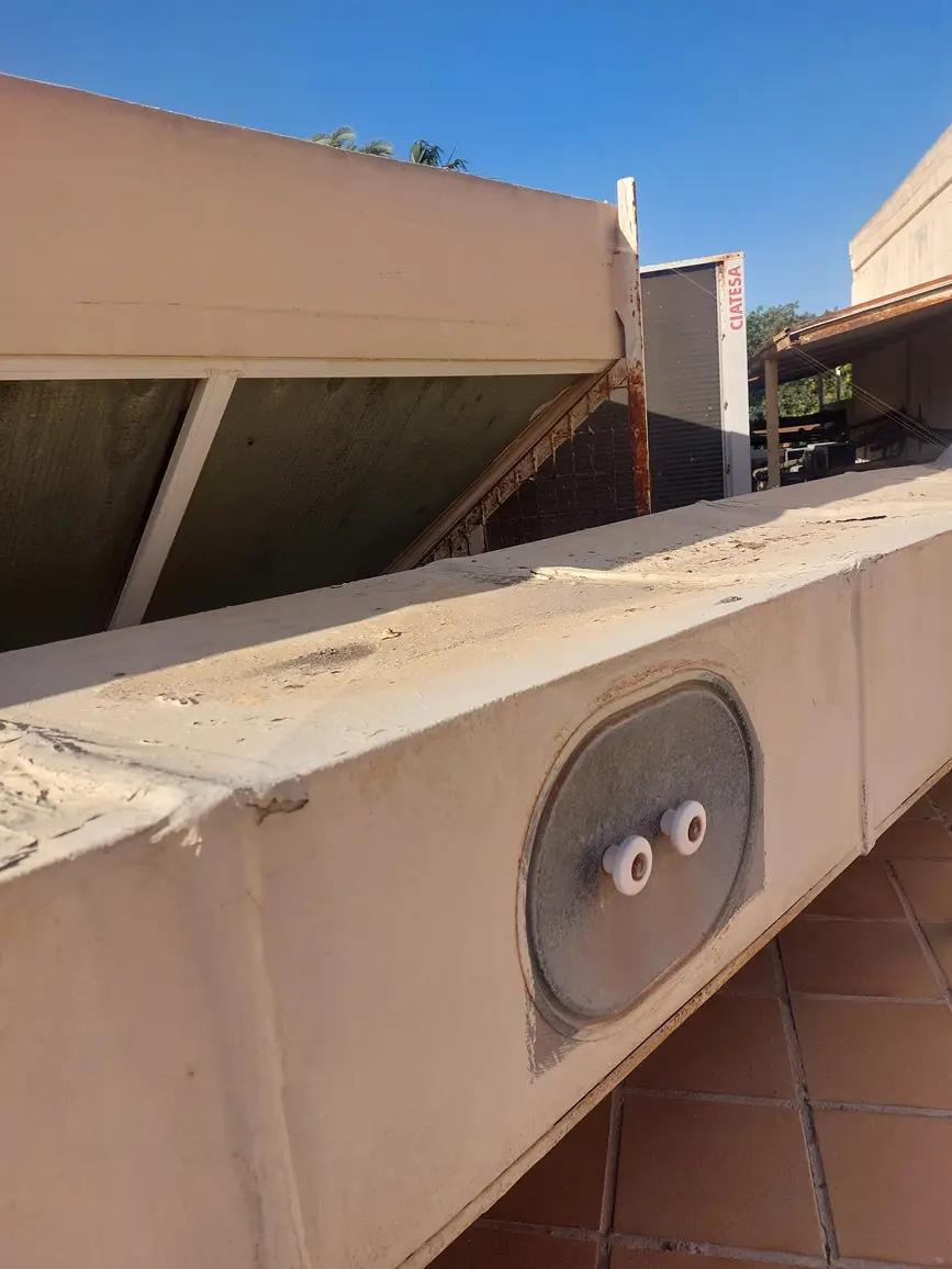 A close-up photo of a weathered, beige concrete ledge with two small white plastic knobs protruding from a circular metal…