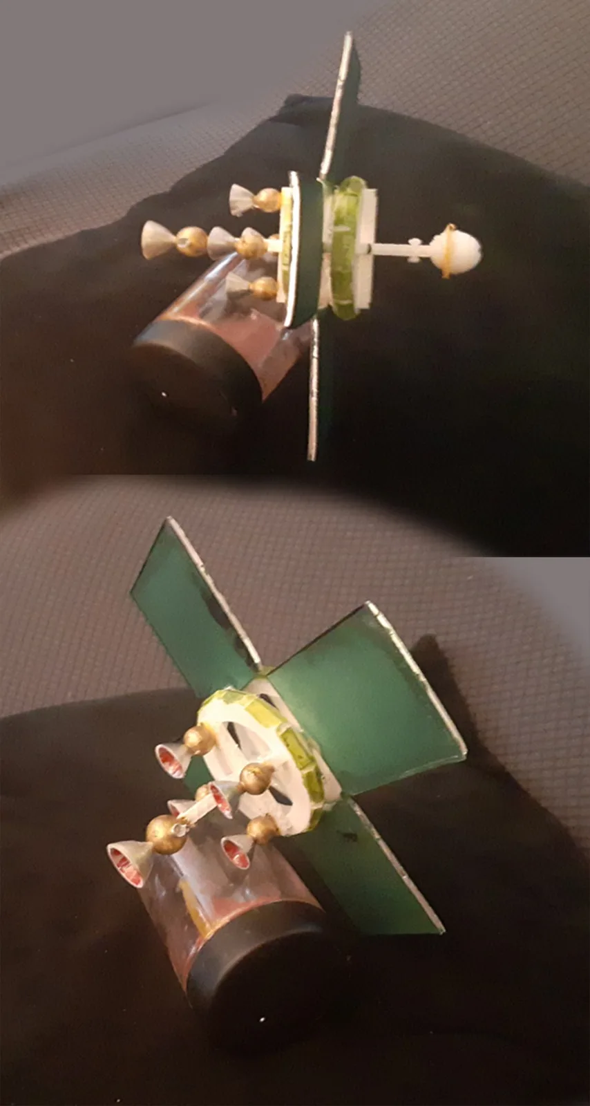 The image shows a homemade satellite model made from a plastic bottle, green cardboard solar panels, and small golden…