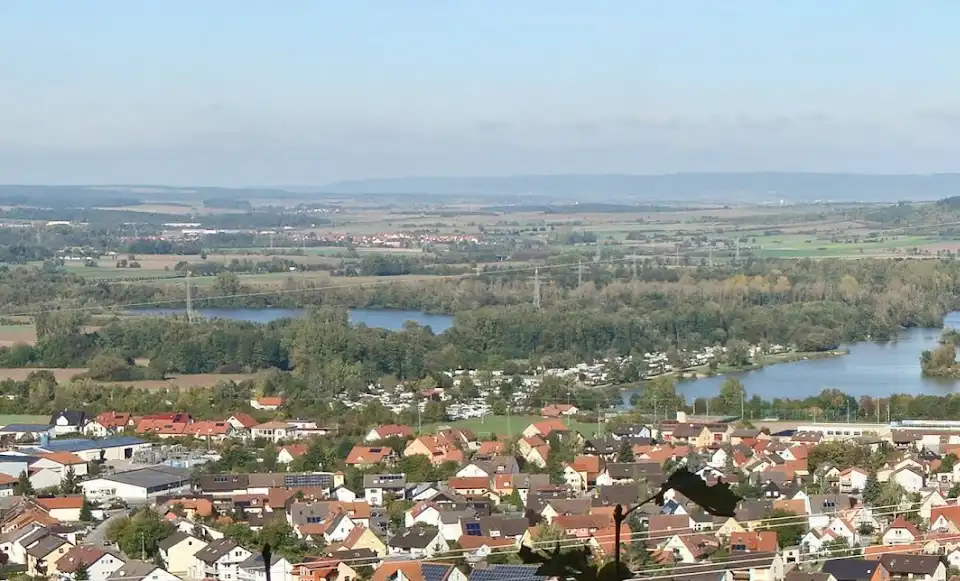 A scenic landscape photo of a town with red-roofed houses, green fields, and a river, overlaid with the text 'i'm not lazy…