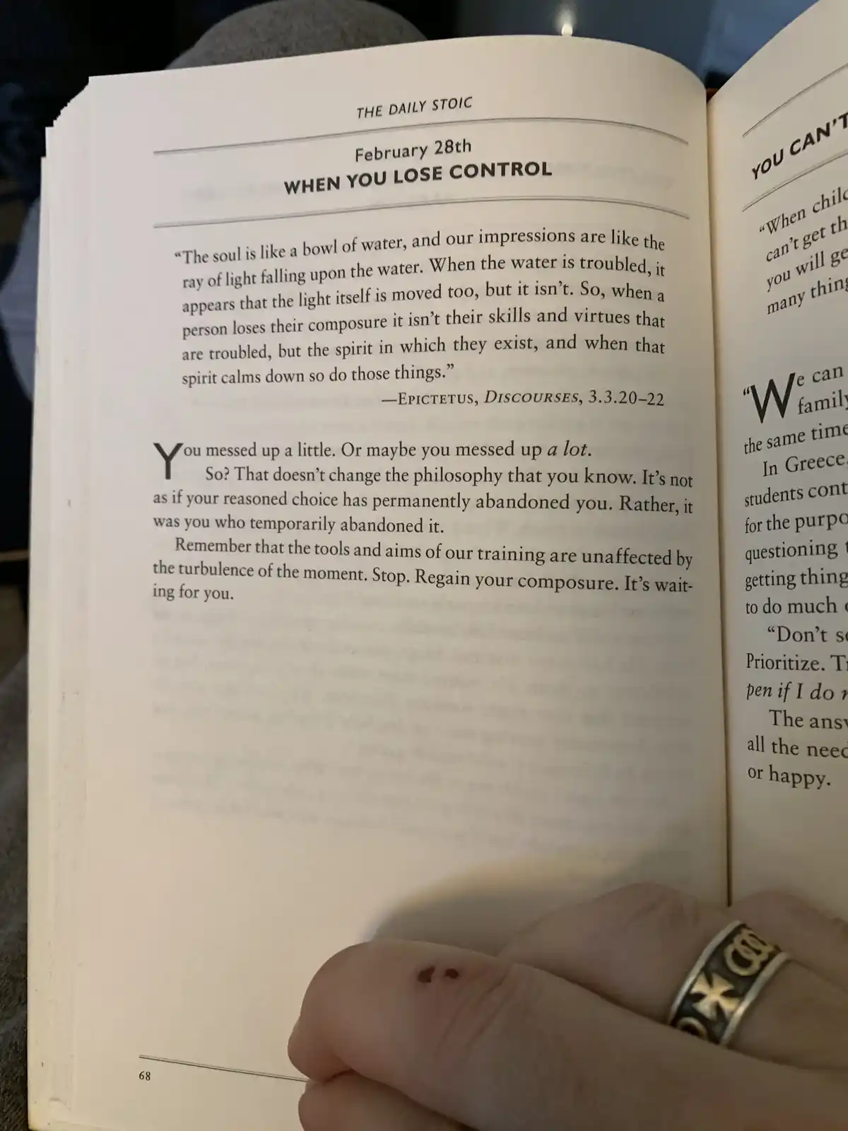 A close-up photo shows a person's hand holding open a book titled 'THE DAILY STOIC' on page 68, dated February 28th with the…