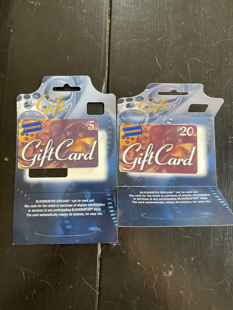 Two vintage Blockbuster gift cards, one $5 and one $20, are shown side-by-side in their original packaging on a dark…