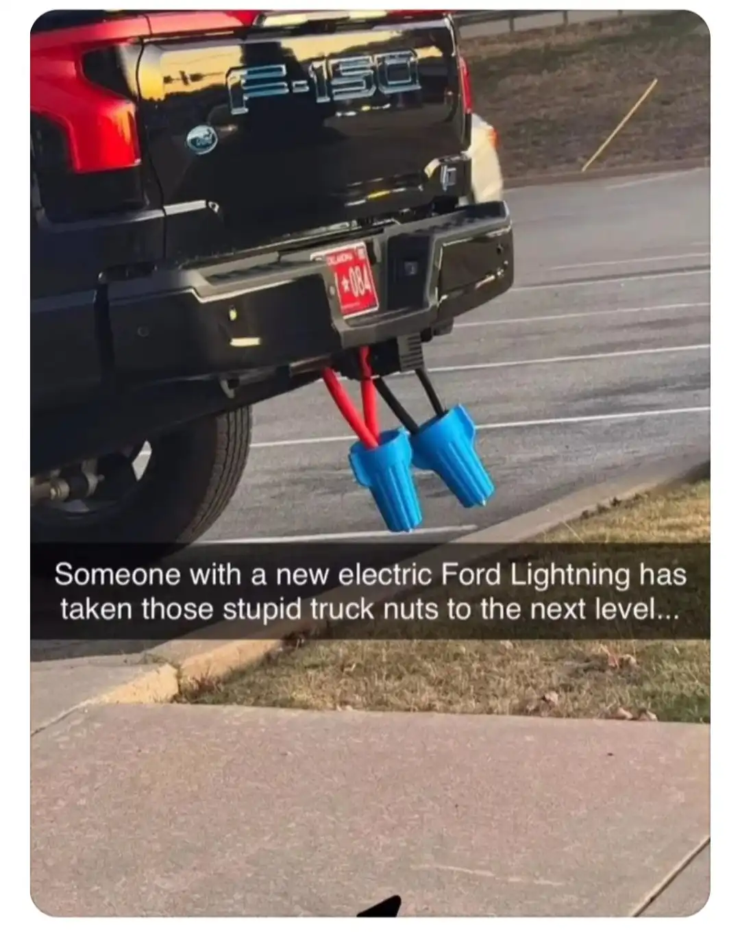 The image shows the rear of a black Ford F-150 pickup truck parked in a lot, with its hitch attached to two large blue…