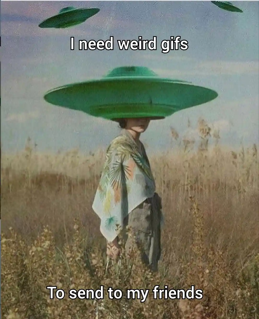 A person stands in a field of tall grass wearing a large green UFO-shaped hat that obscures their face, with two more UFOs…